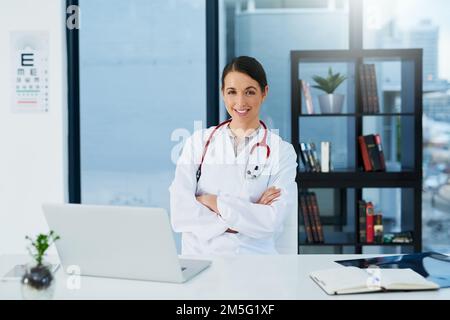 Vertrauen in ihre Fähigkeiten als Ärztin. Porträt einer jungen Ärztin, die mit einem Laptop am Schreibtisch sitzt. Stockfoto