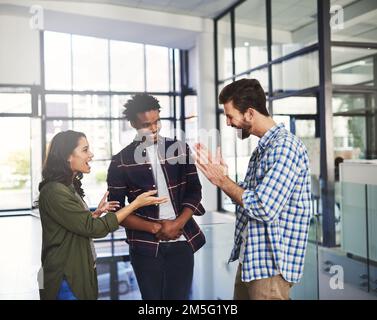 Das ist eine tolle Idee. Drei junge Designer diskutieren in einem modernen Büro. Stockfoto