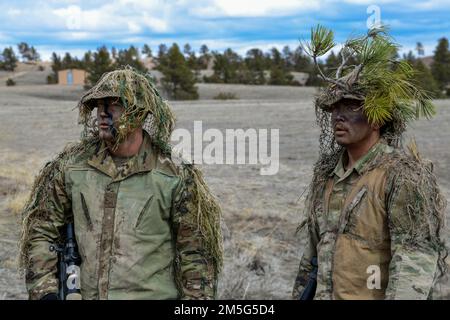 Senior Airman Anjelo Pool und Staff Sgt. Aaron Lee, 341. Geschwader für Raketensicherheitsoperationen, Malmstrom Air Force Base, Montana, demonstrieren am 16. März 2022 Ghillie-Anzüge und ihren Zweck in Camp Guernsey, Wyoming. Ghillie-Anzüge helfen einem Scharfschützen, in ihre Umgebung zu verschwinden und sich vor ihren Gegnern zu verstecken. Stockfoto