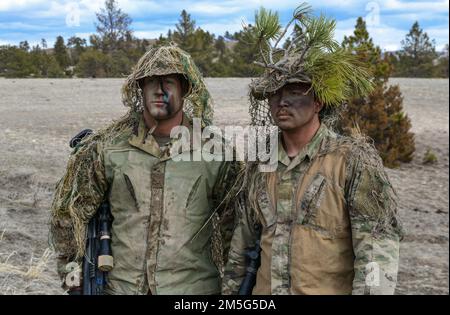 Senior Airman Anjelo Pool und Staff Sgt. Aaron Lee, 341. Geschwader für Raketensicherheitsoperationen, Malmstrom Air Force Base, Montana, präsentieren ihre Ghillie-Anzüge den Verteidigern am 16. März 2022 in Camp Guernsey, Wyoming. Ghillie-Anzüge helfen einem Scharfschützen, in ihre Umgebung zu verschwinden und sich vor ihren Gegnern zu verstecken. Stockfoto