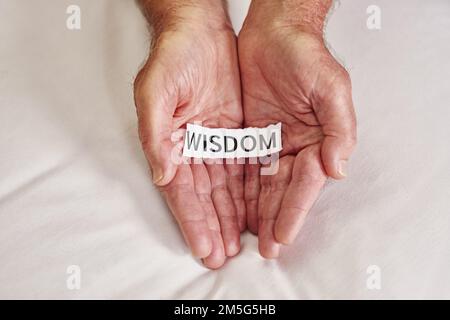 Worte der Weisheit. Eine Person, die ein Stück Papier hält, auf dem das Wort Weisheit steht. Stockfoto