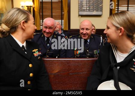 Ens. Amanda Clark aus Las Vegas, der Naval Computer and Telecommunications Area Master Station, Atlantic, links, Und der Logistikspezialist Seaman Ariel Watts aus Dawson, Georgia, der der USS Gerald R. Ford (CVN 78) zugeteilt wurde, spricht während eines Besuchs der Savannah Navy Week am 16. März 2022 mit Mitgliedern der irischen Streitkräfte im Rathaus von Savannah. Die Navy Week ist eine jährliche Reihe von Veranstaltungen, die das ganze Jahr über in verschiedenen US-amerikanischen Städten stattfinden, in denen die Marine nicht präsent ist. Sie bietet den Bürgern die Möglichkeit, mit Seeleuten zu interagieren und mehr über die Navy und ihre Fähigkeiten zu erfahren. Der Flottenausläufer Stockfoto