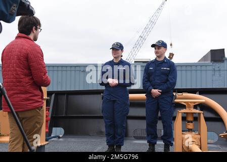 USA Marissa Drees und Leutnant j.g. Kyle Hansen, Crewmitglieder an Bord der Küstenwache Cutter Spar, führen ein Medieninterview über FOCUS, während sie am Pier in Portland, Maine, am 16. März 2022 festgemacht sind. Prior Spar (WLB 403) Matrosen kamen an Bord, um Geschenke zu überreichen und den aktuellen Spar (WLB 206) zu besichtigen. Stockfoto