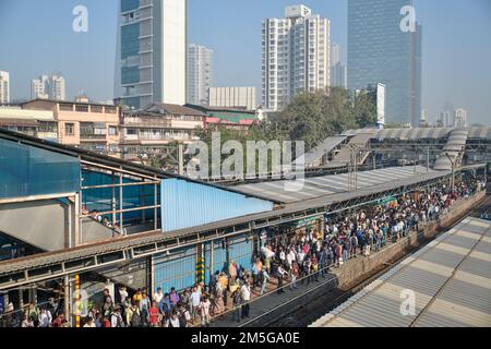 Passagiere, die einen Bahnsteig am Bahnhof Dadar in Mumbai, Indien, überqueren und auf einen Nahverkehrszug warten, der zu ihren Arbeitsplätzen im Süden von Mumbai fährt Stockfoto