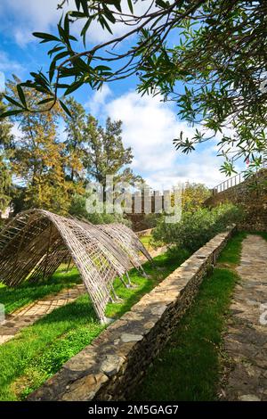 Blick auf den Innenhof mit Rasen und moderner Skulptur im Holzbogen-Schatten. Am Castelo de Alcoutim in der Algarve von Portugal, westlich Stockfoto