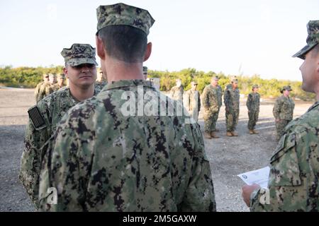 (220316-N-OI810-0057) KEY WEST, Florida (16. März 2022) Cmdr. Orrick Haney, kommandierender Offizier des Naval Construction Battalion (NMCB) 14, Center, Kittel Equipment Operator 3. Class Miguel Rivera, aus Miami, Florida, zugewiesen zu NMCB-14, mit dem 3. Class Petty Officer Insignia während des Morgenquartiers im Boca Chica Field Small Arms Range, Naval Air Station Key West (NASKW), 16. März 2022. Seabees, die der NMCB-14 zugeteilt wurden, reisten nach NASKW, um einen einwöchigen Kurs zu absolvieren, um die Kampfbereitschaft zu erhöhen und Mitglieder der M-18-Pistolen- und M-4-Waffen-Kleinwaffenplattformen zu qualifizieren. NMCB-14 bietet Advan Stockfoto