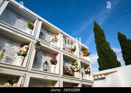 Ein Blick auf einige der vielen mit Blumen verzierten Gräber auf dem katholischen Friedhof. Im Cemitério Paroquial de Vila Nove de Cacela. In der Algarve-Gegend von Stockfoto