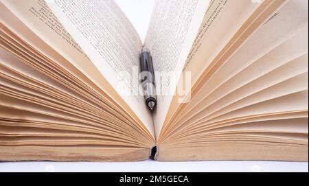 Alte Bücher mit offenem Stift vor einem schmuddeligen, strukturierten Hintergrund. Stockfoto