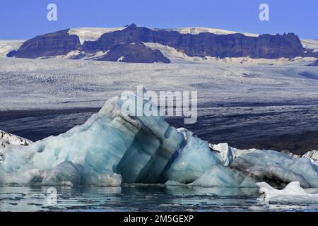 Joekulsarlon, Eisberge, die im See vor dem Gletscher und der felsigen Landschaft schwimmen, Island Stockfoto