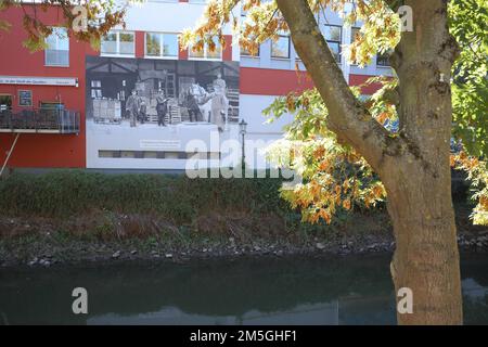 Kurgarten am Nidda Ufer mit Wandgemälde des GRAFITTISKÜNSTLERS am Hassia Mineralwasser Historik Betrieb in Bad Vilbel, Hessen Stockfoto