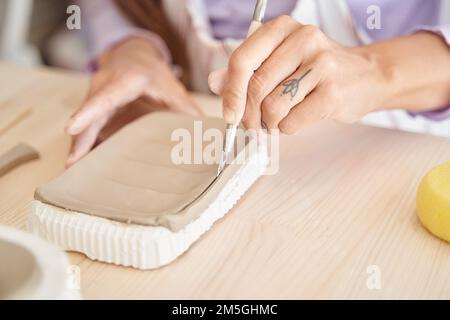 Nahaufnahme einer Frau, die mit Lehm in einer Töpferwerkstatt arbeitet. Handwerk und Hobbys. Stockfoto