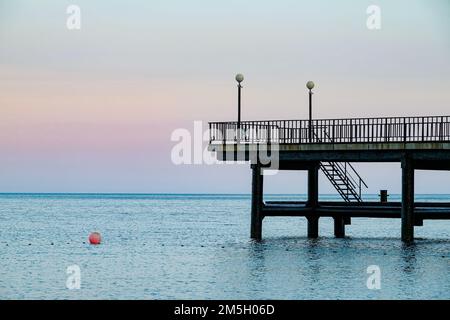 Blick auf das Meer auf einen hölzernen Fischerpier, der sich bis in die schäumenden Wellen des Atlantischen Ozeans erstreckt. Kitty Hawk, Outer Banks, North Carolina. Speicherplatz kopieren. Stockfoto