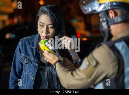 Ein thailändischer Polizist führt einen Fahrer durch einen Alkoholtest mit einem Atemgerät am Check Point in Chiang Mai. Das Zentrum für Prävention und Reduzierung von Straßenverkehrsunfällen wurde während des Neujahrsfestivals 2023 eingerichtet, dem 7-tägigen intensiven Kontrollzeitraum vom 29. Dezember 2022 bis 4. Januar 2023. Mehr als 50.000 Polizeibeamte sollen Kontrollpunkte einrichten, um die Verkehrsgesetze zu vereinfachen und die Sicherheit der Menschen zu gewährleisten. Sie werden während des gesamten Festivals ohne Urlaub arbeiten und sich gemäß der Regierungspolitik auf 4 Gebühren konzentrieren: Fahren unter Alkoholeinfluss, Fahren zu schnell und nicht tragen Stockfoto