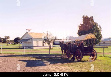 Amish Country Byway - Schulhaus und überdachter Wagen. Vor dem Amish and Mennonite Heritage Center in der Nähe von Berlin wartet ein Pferdewagen auf Sie. In der Ferne steht ein weiß getünchtes, einzimmeriges Schulhaus. Standort: Nordöstlich von Berlin, Ohio (40,570° N 81,784° W) Stockfoto