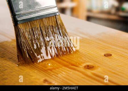 Lack auf Holzplatte mit Pinsel auftragen. Beschichtung und Schutz von Möbeln Stockfoto
