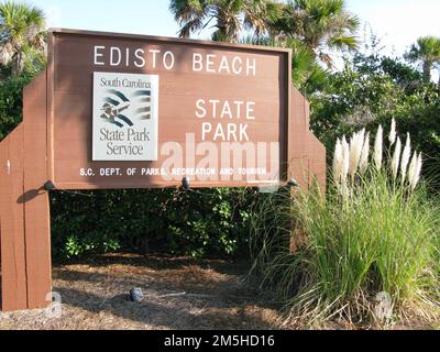 Edisto Island National Scenic Byway - Schild für Edisto Beach State Park. Nach der Ankunft am Ende des Edisto Island Scenic Byway sehen Besucher den Atlantischen Ozean direkt vor sich und ein großes Schild zum Edisto Beach State Park auf der linken Seite. Standort: South Carolina (32,513° N 80,300° W) Stockfoto