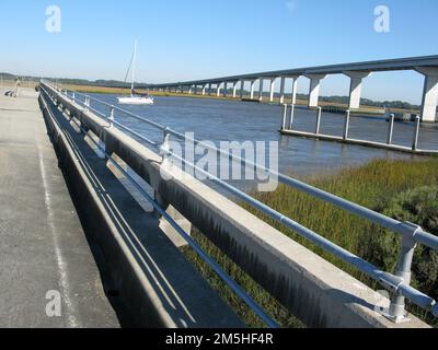 Edisto Island National Scenic Byway - Dawhoo Landing auf dem Atlantic Intracoastal Waterway. Die Brücke bei Dawhoo Landing durchquert das kristallklare Wasser und frisches grünes Gras. Unter der Brücke bietet eine öffentliche Bootsanlegestelle Zugang zum Wasser sowie Blick aus der Nähe auf Pelikane und Boote. Der Reisende kann auch Krabbenfischen, angeln oder ein Picknick machen. Standort: Dawhoo Landing, South Carolina (32,636° N 80,340° W) Stockfoto