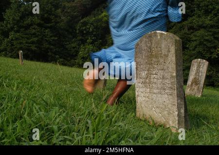 Harriet Tubman Underground Railroad Byway – Führt Durch Mt. Schöne Grabsteine Auf Dem Friedhof. Zwischen den Gräbern des Mt. Der angenehme Friedhof, ein Harriet Tubman-Nachspieler, flieht durch die Grabsteine und nasses Gras in die Freiheit. Mt. Angenehm, Maryland Stockfoto
