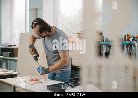 Tischler Bohrer ein Loch mit einer elektrischen Bohrmaschine Stockfoto