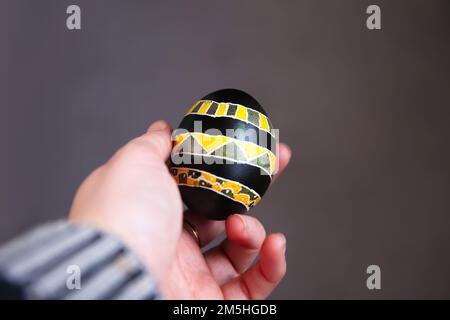 Unschärfe-Ostereier in der weiblichen Hand. Nahaufnahme Ostereier pastellfarben auf grauem Hintergrund. Minimales Osterfest-Konzept, gefärbt Stockfoto