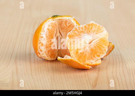 Halbgeschälte Mandarine und Mandarinenscheibe auf Holzhintergrund. Speicherplatz kopieren. Stockfoto