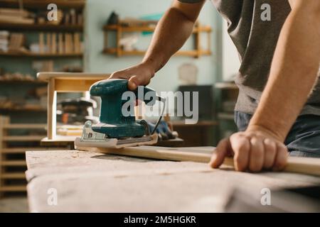 Die Schleifmaschine poliert die Planke aus Holz. Stockfoto