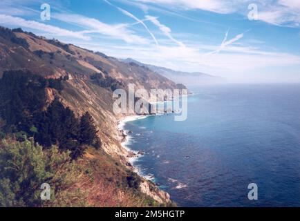 Route 1 - Big Sur Coast Highway - nach Süden auf Route One. Wolken und Flugzeugkontrast erzeugen Muster am Himmel über der Pazifikküste. Standort: Kalifornien (35,779° N 121,329° W) Stockfoto