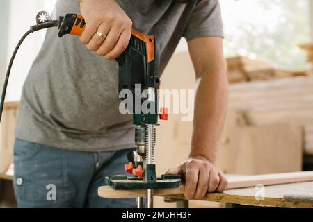 Der Master arbeitet in ein Studio und ein Loch in einer Platte bohren. Stockfoto