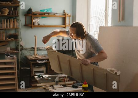 Ein Zimmermann stellt in seiner Werkstatt ein Kletterset Montessori für Kinder her. Stockfoto