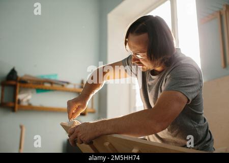 Ein Zimmermann stellt in seiner Werkstatt ein Kletterset Montessori für Kinder her. Stockfoto