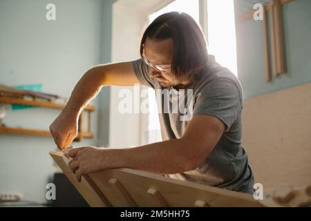 Ein Zimmermann stellt in seiner Werkstatt ein Kletterset Montessori für Kinder her. Stockfoto