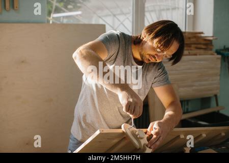 Ein Zimmermann stellt in seiner Werkstatt ein Kletterset Montessori für Kinder her. Stockfoto