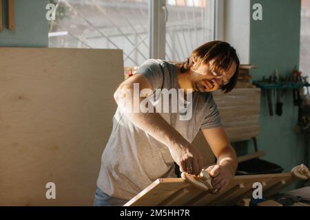 Ein Zimmermann stellt in seiner Werkstatt ein Kletterset Montessori für Kinder her. Stockfoto