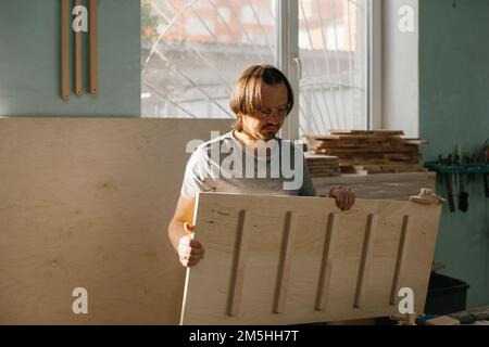 Ein Zimmermann stellt in seiner Werkstatt ein Kletterset Montessori für Kinder her. Stockfoto