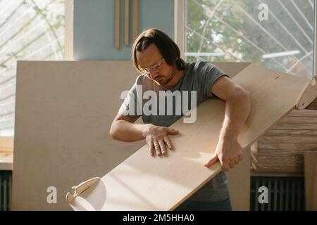 Ein Zimmermann stellt in seiner Werkstatt ein Kletterset Montessori für Kinder her. Stockfoto