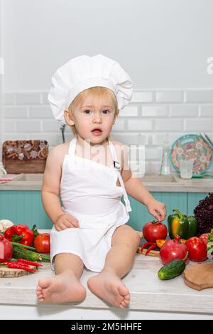 Ein süßer kleiner Junge im Koch-Kostüm kocht mit Emotionen. Hochwertiges Foto Stockfoto