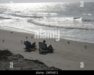 Edisto Island National Scenic Byway - ruhiger Morgen am Edisto Beach. Der Edisto Island National Scenic Byway endet am Atlantischen Ozean und dem Haupteingang zum Edisto Beach State Park. Kein Besuch ist komplett ohne einen Spaziergang auf dem Sand, um Muscheln, Fossilien und Haifischzähne zu sammeln... oder einfach nur still zu sitzen, während die Sonne die Wellen in ein Meer von Diamanten verwandelt. Standort: South Carolina (32,503° N 80,296° W) Stockfoto