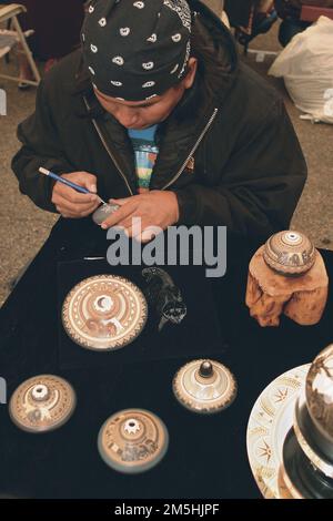 Trail of the Ancients - Ein indianischer Töpferkünstler auf dem Indian Art Market. Der Indian Art Market, der Teil des jährlichen Indian Arts and Western Culture Festival im Mesa Verde Country ist, beherbergt 40 indianische Künstler. Dieser Künstler malt Details auf Töpfen, die zum Verkauf bereit sind. Standort: Colorado (37,476° N 108,546° W) Stockfoto