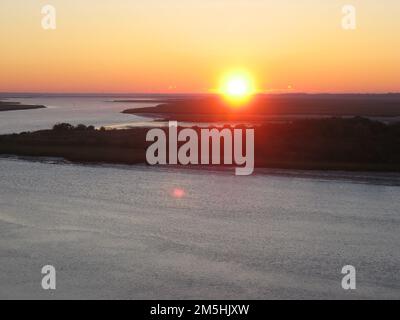 Edisto Island National Scenic Byway - Sonnenaufgang vom Crest of McKinley Washington, Jr., Bridge. Die Sonne geht in Orange, Rot und Pink über dem Intracoastal Waterway entlang des Edisto Island National Scenic Byway auf. Standort: South Carolina (32,599° N 80,346° W) Stockfoto