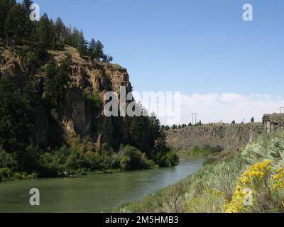 Pioneer Historic Byway - Hells Canyon Reservoir. Das Hells Canyon Reservoir fließt friedlich am Fuße der Felsen entlang. Wildblumen blühen im Vordergrund. Lage: Hells Canyon Reservoir, Idaho (45,237° N 116,703° W) Stockfoto