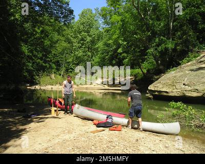 Red River Gorge Scenic Byway - Kanus in der Red River Gorge. Zwei Kanufahrer am Strand paddeln durch die Red River Gorge von Kentucky. Grüne Bäume, Pflanzen und große Steine flankieren den Fluss. Lage: Red River, Kentucky Stockfoto