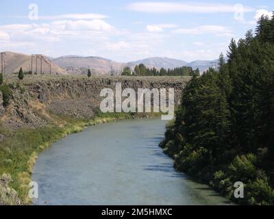 Pioneer Historic Byway - in die Erde gemeißelt. Das Hells Canyon Reservoir schlängelt sich durch die Landschaft in der Nähe von Sheep Rock. Immergrüne Flüsse füllen ein Flussufer, schräge graue Felsen bilden das andere. Lage: Hells Canyon Reservoir, Idaho (45,143° N 116,729° W) Stockfoto