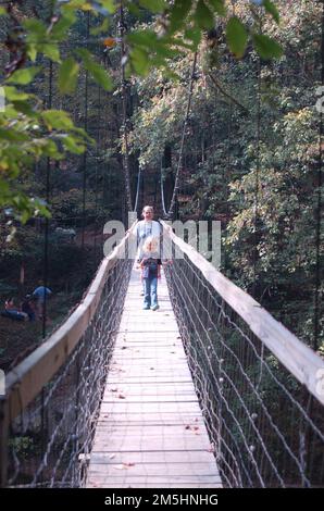 Red River Gorge Scenic Byway - Hängebrücke auf dem Sheltowee Trail. Ein Vater hilft seiner Tochter, den Red River auf einer Fußgängerbrücke auf dem Sheltowee Trace Trail im Daniel Boone National Forest zu überqueren. Lage: Sheltowee Trace Trail, Kentucky Stockfoto