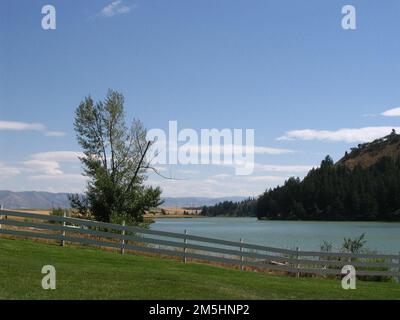 Pioneer Historic Byway - Weidezäune und Blue Skies. Ein Weidezaun umrahmt das blaue Wasser des Hells Canyon Reservoir. Der blaue Himmel blickt auf den Tatort. Lage: Hells Canyon Dam, Idaho (43,004° N 111,714° W) Stockfoto