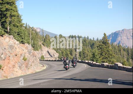 Volcanic Legacy Scenic Byway – Reiten auf Volcanic Legacy im Crater Lake National Park. Eine Gruppe von Motorradfahrern passiert einen Aussichtspunkt auf dem Weg zum Curvy Rim Drive mit seinem Steinzaun im Crater Lake National Park. Lage: Crater Lake National Park, Oregon (42,940° N 122,180° W) Stockfoto