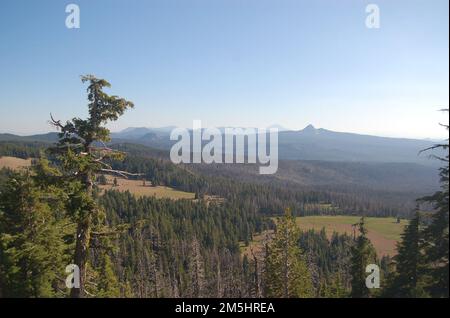 Volcanic Legacy Scenic Byway - Eine Kaskade von Vulkanen vom Rim Drive Overlook. Der kalifornische Mount Shasta ist am Horizont kaum zu sehen, wenn man den Aussichtspunkt auf dem Rim Drive des Crater Lake National Park besteigt. Andere vulkanische Gipfel und Kegel in der Cascade Range sind sichtbarer. Lage: Crater Lake National Park, Oregon (42,940° N 122,179° W) Stockfoto