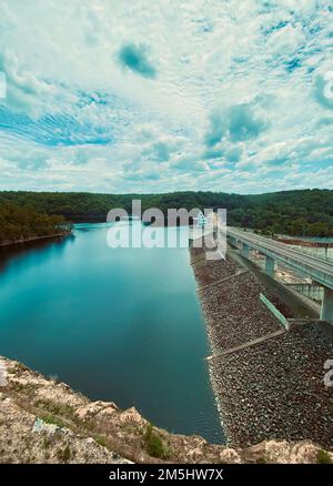 Ein vertikales Bild des Warragamba Dams unter blauem, wolkigen Himmel und Sonnenlicht in Sydney, Australien Stockfoto