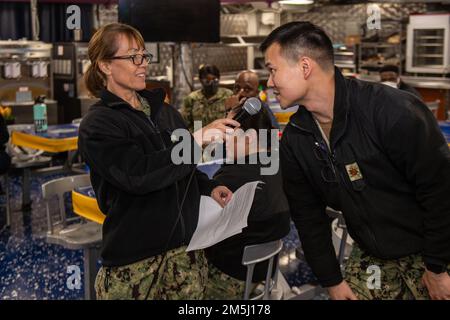 220318-N-SI601-1071 YOKOSUKA, Japan (18. März 2022) Capt. Carolyn Rice, kommandierender Offizier der USA Marinekrankenhaus Yokosuka aus Valley Forge, Pennsylvania, fragt Lieutenant Commander. Long Tran, stellvertretender Versorgungsbeamter, eine Frage zu weiblichen Rollen in der Navy während einer Feier des Women's History Month auf den hinteren Kassendecks der USA Der einzige vorwärtsgesetzte Flugzeugträger der Navy USS Ronald Reagan (CVN 76). Bei der diesjährigen Veranstaltung wurden die Leistungen von Frauen in der Geschichte und in der heutigen Welt hervorgehoben und das Thema „Frauen für Heilung und Hoffnung“ thematisiert. Ronald Reagan, der Flagsh Stockfoto