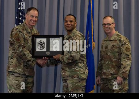 Master Sgt. Phenice Cooper, Center, 436. Flugstaffel, Verkehrsmanagement-Superintendent, nimmt seine Senior Master Sergeant Beförderungsplakette von Oberst Matt Husemann, links, 436. Und Chief Sgt. Timothy Bayes, 436. AW-Kommandochef, während der Senior Master Sergeant Promotion Release Party auf der Dover Air Force Base, Delaware, 18. März 2022. Cooper war einer von sieben Master Sergeants bei Dover AFB, die für die Beförderung zum Senior Master Sergeant im 22E8-Beförderungszyklus ausgewählt wurden. Stockfoto