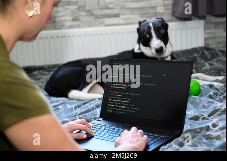 Kodierung im Haus, eine Frau schreibt Code auf einem Laptop für eine App oder Website, während sie von zu Hause aus arbeitet Stockfoto
